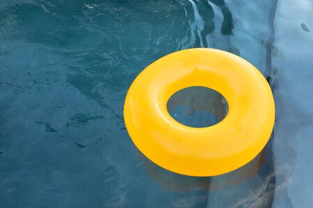 Weekend at home together. High angle view of a yellow inflatable ring floating in a swimming pool. Home and lifestyle weekend activities.の写真素材