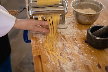 Side view mid section of a Caucasian female chef wearing chefs whites and a black apron preparing...