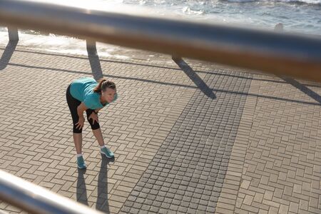 High angle side view of a mature middle aged Caucasian woman working out on a promenade on a sunny...