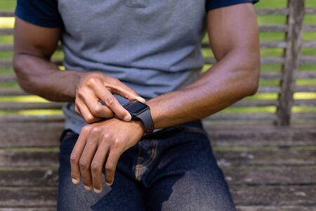 Front view mid section of an African American man checking his smartwatchの写真素材