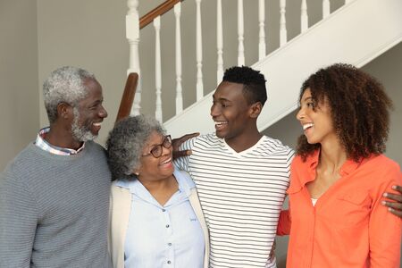 Front view of a happy senior African American couple with their adult children at home