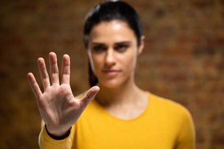 Front view of a Caucasian woman with her palm facing camera, touching a virtual interactive screen.