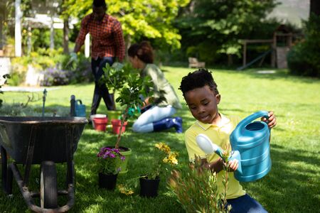 Front view of an African American boy in the garden watering plantsの写真素材