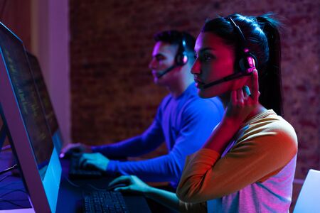 Side view of a Caucasian man and a mixed race woman working late in a customer support office in the...