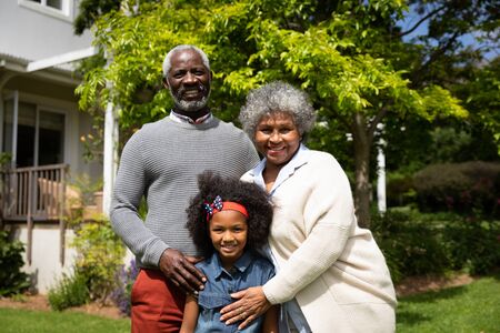 Portrait of smiling African American grandmother and grandfather in the garden with their granddaughter, smiling to camera.の写真素材
