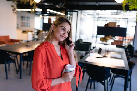 Side view of a Caucasian businesswoman with long blond hair, wearing smart clothes, working in a...