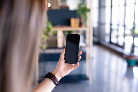 Rear view mid section of a businesswoman working in the modern office, wearing a smartwatch and using a smartphone..の写真素材