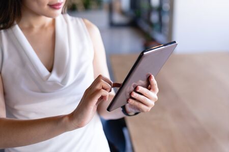 Front view mid section of a businesswoman working in the modern office, wearing smart clothes, and using a tablet.の写真素材