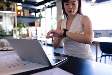 Front view of an Asian businesswoman wearing smart clothes, working in the modern office, standing...