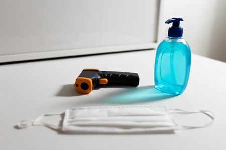 Close up of a sanitizer, thermometer and white face mask protection against pandemic coronavirus...