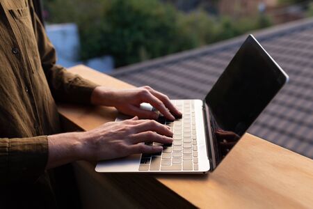 Caucasian woman spending time at home self isolating and social distancing in quarantine lockdown during coronavirus covid 19 epidemic, using a laptop on her balconyの写真素材