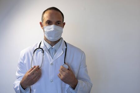 Portrait of a Caucasian man, wearing doctor uniform and a stethoscope on his shoulders, wearing a...