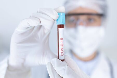 Caucasian female healthcare worker wearing a lab coat, face mask and surgical gloves against...