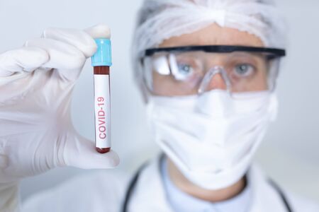 Portrait of a Caucasian female healthcare worker wearing a lab coat, face mask and surgical gloves...