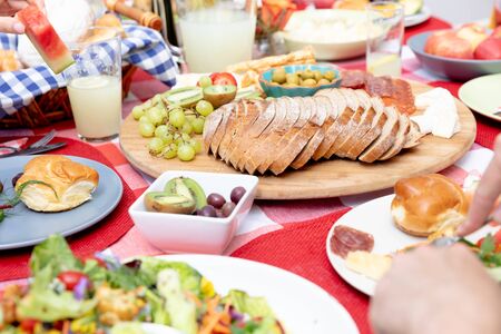 Mid section of a Caucasian three generation family having a lunch in the garden on a sunny day, sitting by a table.の写真素材