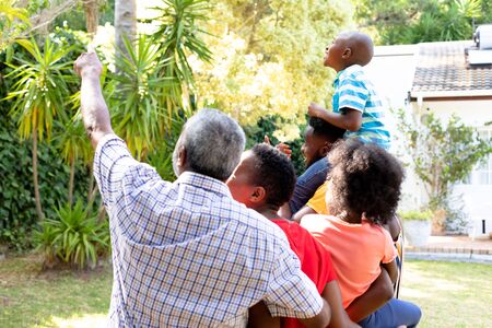 Rear view of a three generation African American family spending time in their garden on a sunny...