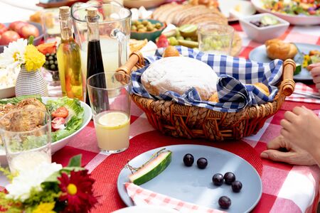 Mid section of a Caucasian three generation family having a lunch in the garden on a sunny day, sitting by a table and interacting.の写真素材