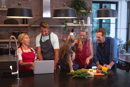 Multi-generation Caucasian family enjoying their time at home together, standing by a table in a...