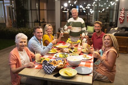 Multi-generation Caucasian family enjoying their time at home together, sitting by a table, talking,...