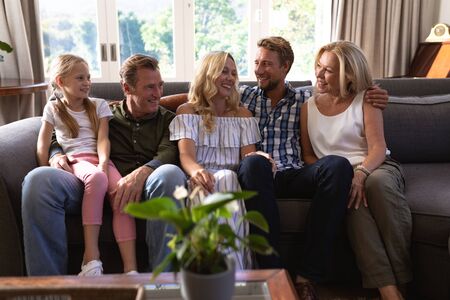 Multi-generation Caucasian family enjoying their time at home, sitting on a couch together, looking...