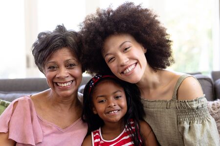 Multi-generation mixed-race family enjoying their time at home together, sitting on a couch,...
