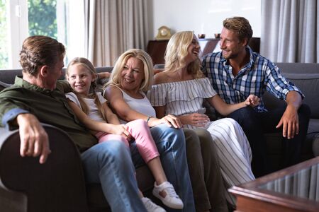 Multi-generation Caucasian family enjoying their time at home, sitting on a couch together, looking...
