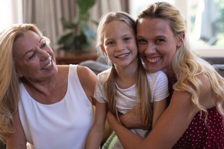 Caucasian woman, her daughter and mother enjoying their time at home together, sitting on a couch,...