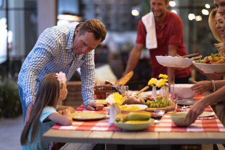 Multi-generation Caucasian family enjoying their time at home together, setting a table, looking at...
