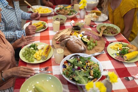 Multi-generation Caucasian family enjoying their time at home together, sitting by a table, putting...