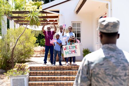 African American three generation family standing by their house with a banner, welcoming an African American solider wearing uniform.の写真素材