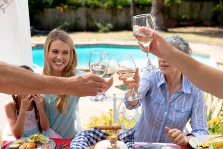 Caucasian three generation family spending time together in the garden on a sunny day, sitting by a...