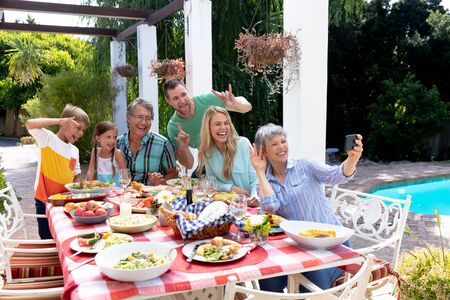 Caucasian three generation family spending time together in the garden on a sunny day, sitting by a...