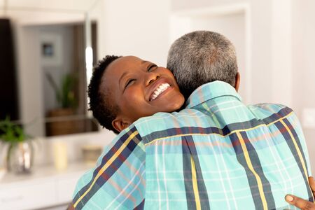 Senior African American couple spending time at home, embracing and smiling. Social distancing and self isolation in quarantine lockdown.の写真素材