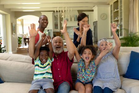Portrait of a multi-generation mixed race family at home in the living room, gathered together on a...