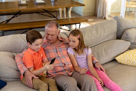 High angle view of a senior Caucasian man at home in the living room sitting on the couch with his...