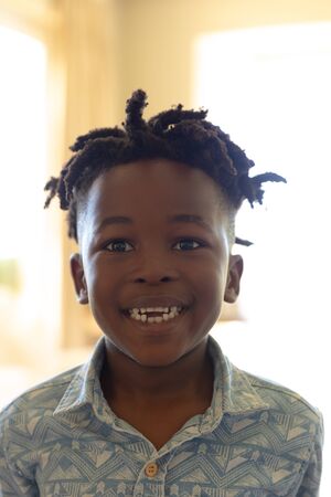 Portrait close up of an African American boy with short hair and dreadlocks, wearing a blue...