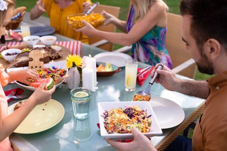 Side view close up of a Caucasian man sitting at a table serving himself food during a family meal...