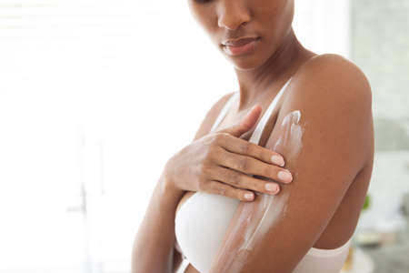 Mixed race woman spending time at home self isolating and social distancing in quarantine lockdown during coronavirus covid 19 epidemic, taking care of her arms skin, in her bathroom.の写真素材