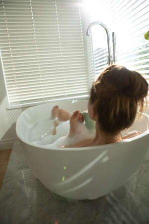 A Caucasian woman spending time at home, having a foamy bath, drinking coffee. Lifestyle at home...