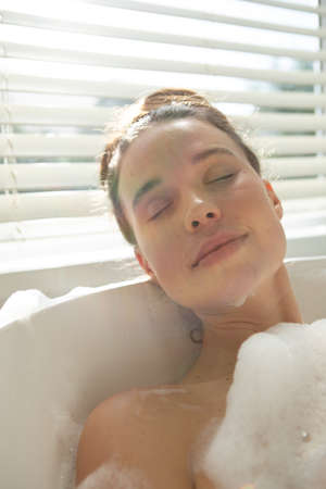 A Caucasian woman spending time at home, having a foamy bath, relaxing. Lifestyle at home isolating,...