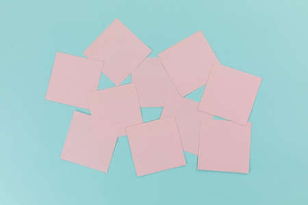Close up top view of ten pink sheets of paper sticky memo notes in one size, arranged on a plain...