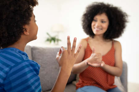 Mixed race mother with son enjoying family time together at home, social distancing and self...