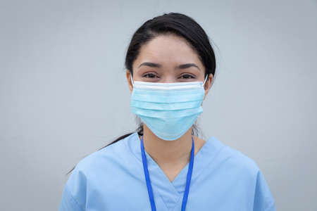 Portrait of confident mixed race female medical professional wearing face mask and scrubs looking to camera. Social distancing and hygiene in the workplace during Coronavirus Covid 19 pandemic.の写真素材