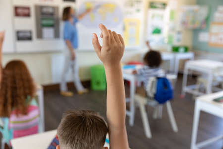 Caucasian female teacher wearing face mask at school, teaching children at school classroom. Education back to school health safety during Covid19 Coronavirus pandemic.の写真素材
