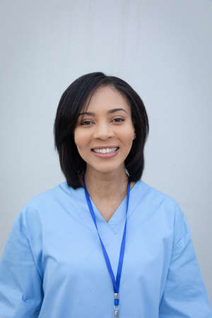 Portrait of confident mixed race female medical professional wearing scrubs smiling to camera....