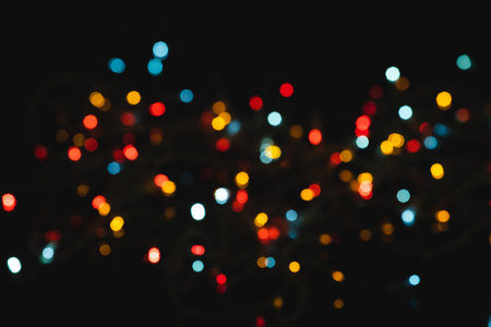 Multiple multi coloured red, blue, yellow out of focus spots of light on black background. Colour, Christmas and celebration concept.の写真素材