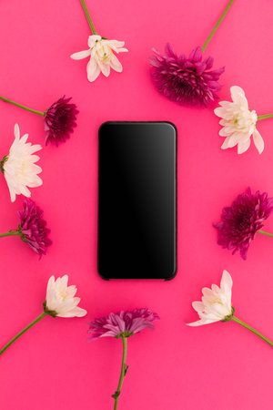 Smartphone with blank screen and pink and white flowers on pink background. technology connection romance valentine's day copy space.の写真素材