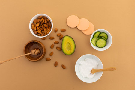 Avocado and bowls of almonds and salad ingredients on orange background. fresh healthy whole food...
