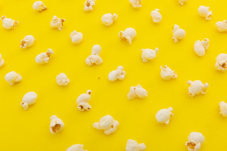 High angle view of popcorn in multiple rows on yellow background. fun party food sweet treat snack concept.の写真素材