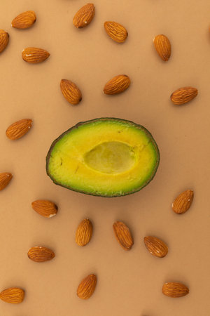 Half of avocado and scattered almonds on orange background. fresh healthy whole food copy space...